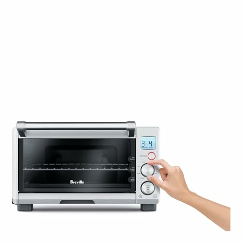 Hand adjusting settings on a compact toaster oven.