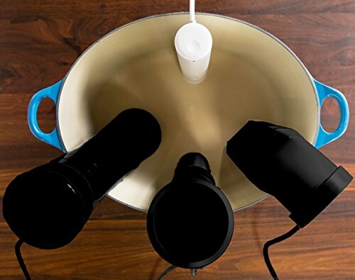 Three sous vide cookers in a large pot on a wooden surface.